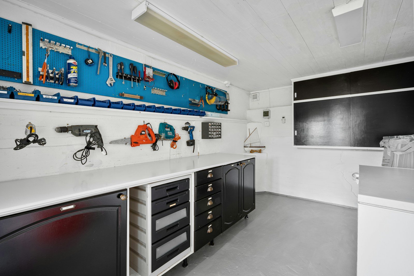 Garage workbench with black cabinets and tool wall