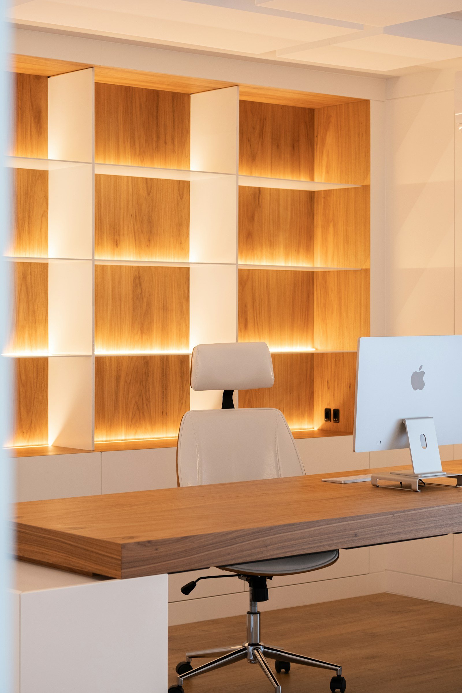 Home office with backlit wood shelving and desk