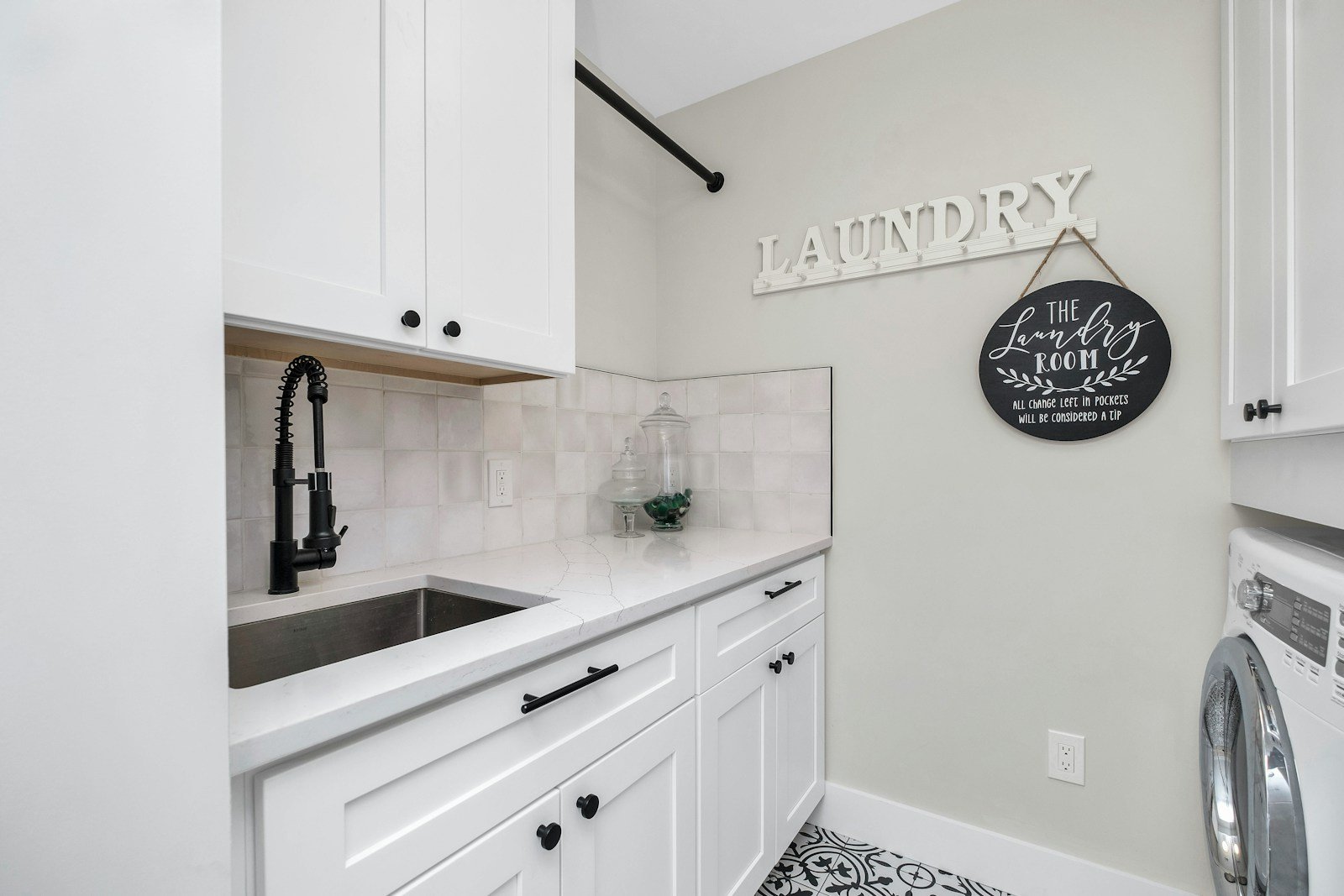 White laundry room cabinets with sink and black hardware