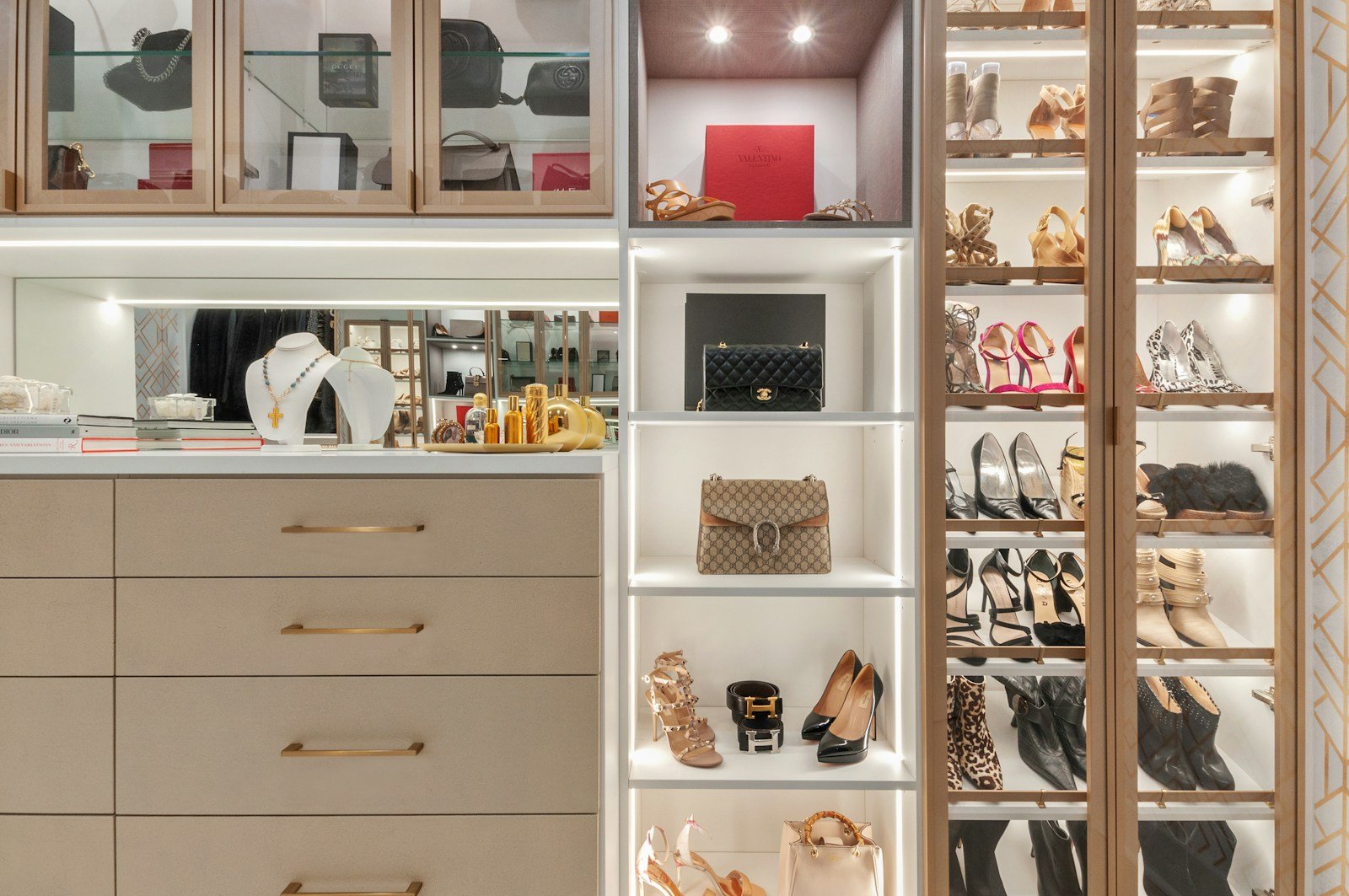 Custom walk-in closet with lit shelving, handbag display and drawers