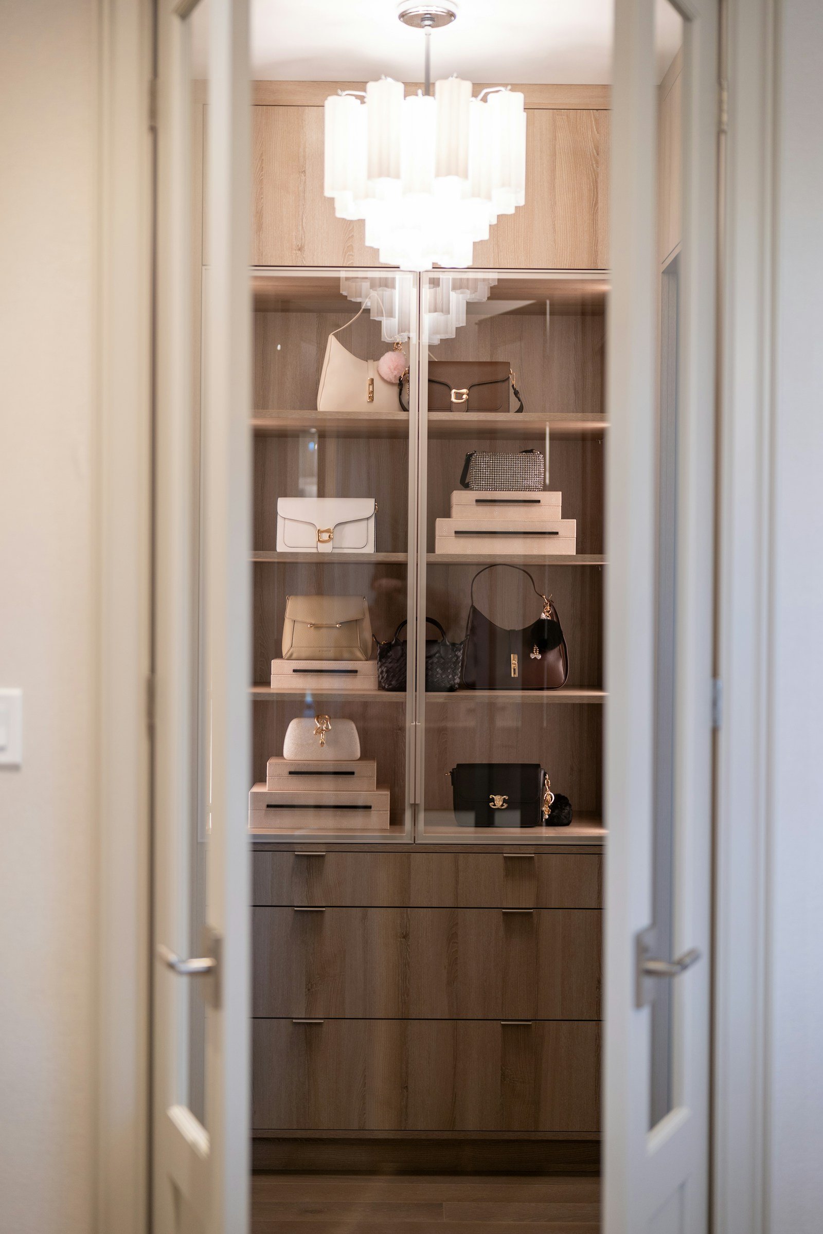 Walk-in closet handbag display with warm lighting and drawers